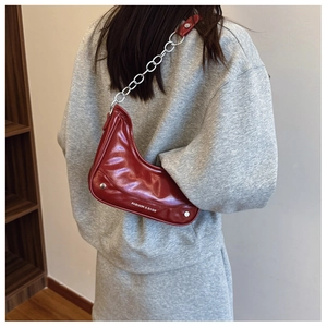 Detailed view of red glossy underarm bag with chunky silver chain and fashion text