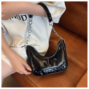 Detail of black crescent hobo bag featuring glossy finish and silver chain strap