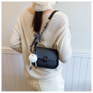 Détail du sac à main noir avec poignée en foulard de soie et breloque peluche rigolote