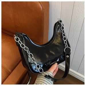 Macro detail of glossy black hobo bag featuring a silver chain and embossed fashion text