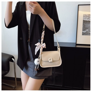 Détail d'un sac bandoulière en cuir PU beige avec bandoulière en soie et pendentif peluche