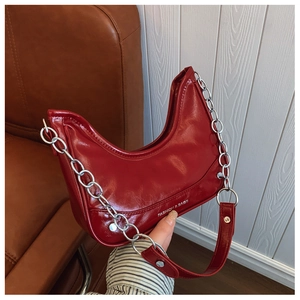Detail of dark red crescent bag in glossy patent leather with thick silver chain handle