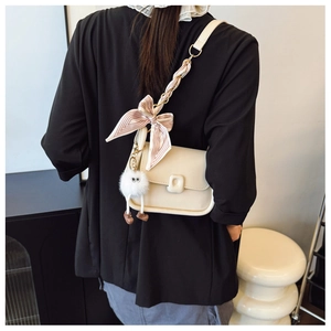 Détail du sac à bandoulière en cuir blanc avec sangle en soie et breloque peluche
