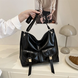 Large black glossy motorcycle tote bag with dual front pockets on a minimalist home background