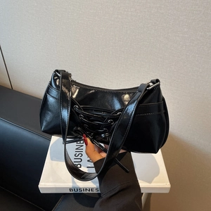 Glossy black baguette bag with ballet style lace-up detail and wide shoulder strap