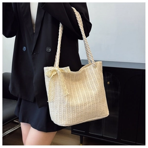 Detail of beige straw tote bag with white rope handles and delicate lace bow accent