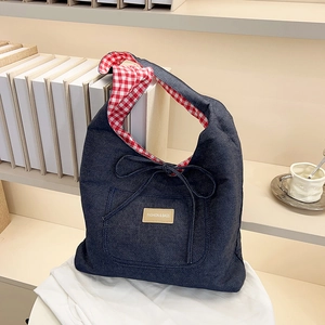 Blue denim tote bag with red checkered lining and a decorative bow on white fabric