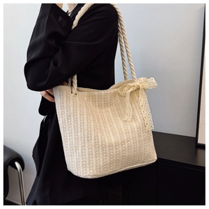 Detail of woven straw tote bag featuring vertical texture and beige lace bow decoration