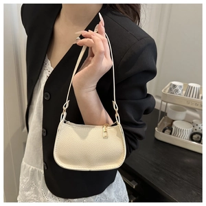 Close-up of off-white lychee pattern leather shoulder bag worn by model in casual setting