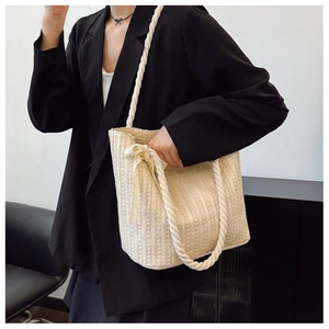 Detail of off-white straw tote bag featuring thick cotton rope straps and lace bow