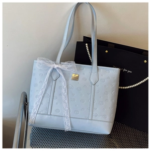 Détail du sac cabas bleu clair avec motifs gaufrés et grand nœud en dentelle blanche