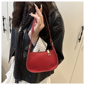 Detail of red textured leather mini handbag with gold zipper on a model shoulder