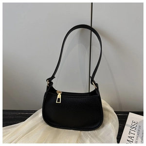 Detail of black litchi grain leather shoulder bag with gold zipper and minimalist design