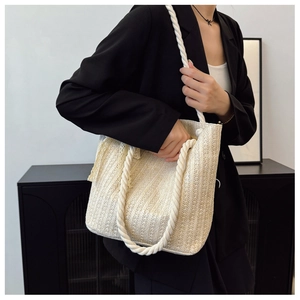 Detail of a beige woven tote bag with thick cotton rope handles in a casual style