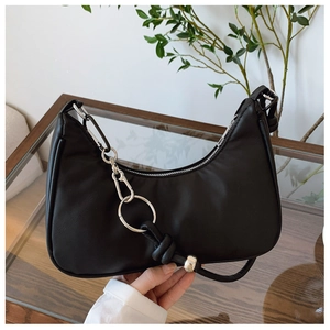 Détail du sac croissant noir avec chaîne à anneaux argentés et texture en cuir mat
