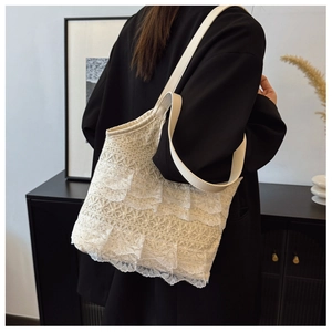 Detailed view of cream lace hobo bag featuring elegant ruffled tiers and leather handle