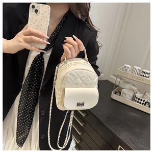 Detail of a quilted mini crossbody bag in cream leather featuring a metal chain strap