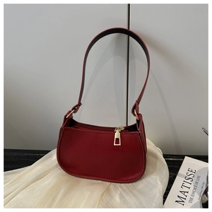 Detail of red litchi texture baguette bag with golden metal zipper and minimalist strap
