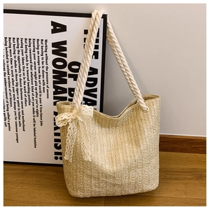 Detail of straw woven tote with white rope handles and decorative lace bow accent