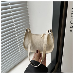 Close-up of cream baguette bag with litchi grain texture and gold zipper details