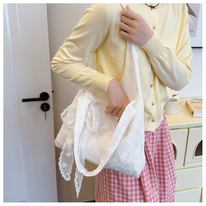 Detailed close-up of white lace floral embroidery on a large canvas hobo tote bag