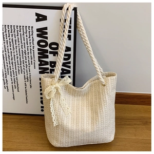 Detail of cream woven tote bag featuring a lace bow and thick cotton rope handles
