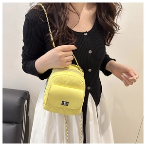 Macro detail of quilted yellow mini backpack featuring a silver metal twist lock closure