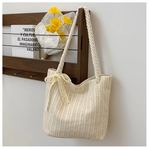 Detail of straw tote bag with cream ribbon bow and white cotton rope handles