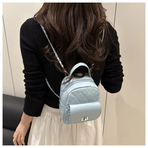 Detail of light blue quilted mini backpack featuring silver chain straps on a female model