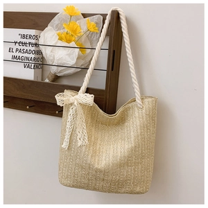 Close-up of woven straw tote bag with cotton rope handles and lace bow decoration