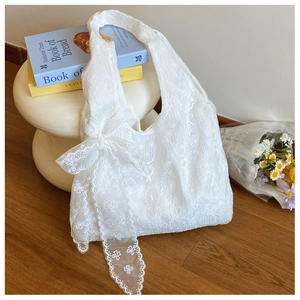 Detail view of the intricate white floral lace embroidery and soft ribbon on the tote bag