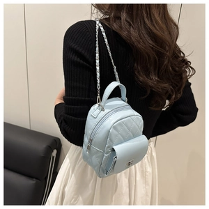 Light blue quilted mini backpack with silver chain straps shown on model in indoor setting