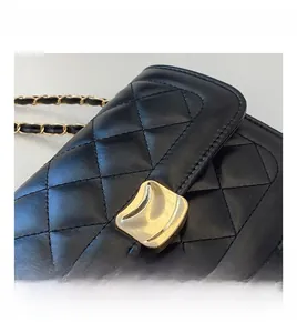 Close-up of black quilted leather bag with unique gold clasp and chain strap