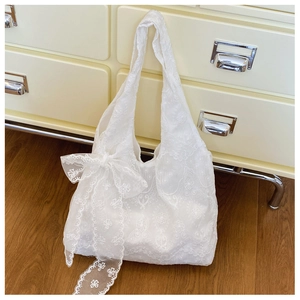 Detailed macro shot of white floral lace texture and ribbon bow on a large tote bag