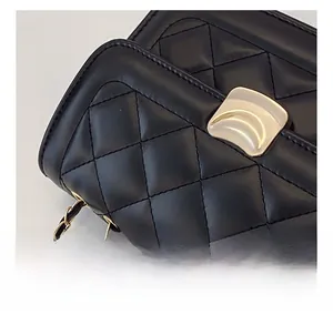 Detail of black quilted leather texture with golden half-moon metal buckle and chain strap