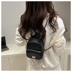 Close-up of black quilted mini backpack with chain straps and silver twist lock on model