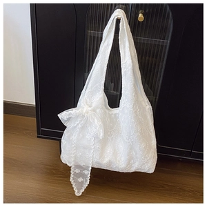 Detail of white lace flower embroidery and large bow on high-capacity canvas tote bag