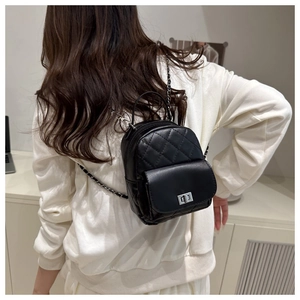 Detail of a mini quilted black backpack featuring a silver chain strap and metal turn-lock