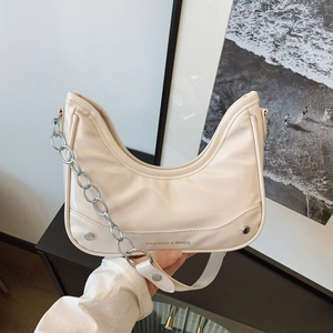 Cream pleated underarm bag with silver chain strap shown in a modern lifestyle setting