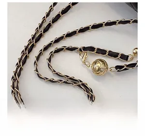 Close-up of adjustable black leather and gold chain shoulder strap with metal ball buckle