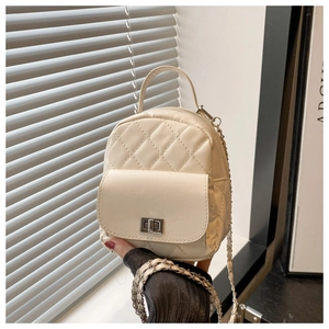 Detail of beige quilted mini backpack featuring metal twist lock and chain strap