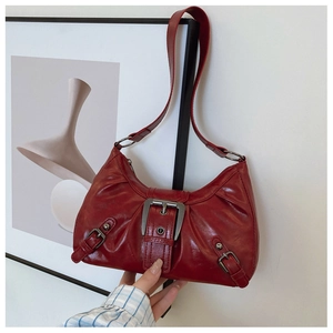 Detail of vintage red pleated shoulder bag featuring wide silver buckle and retro PU leather