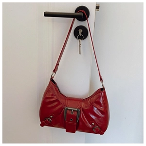 Detail of red distressed leather hobo bag featuring large decorative metal buckle