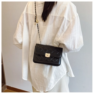 Detail showing classic black quilted texture and golden crescent clasp on chain bag