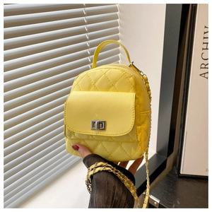 Close-up of a bright yellow quilted mini backpack with a silver twist-lock and chain strap