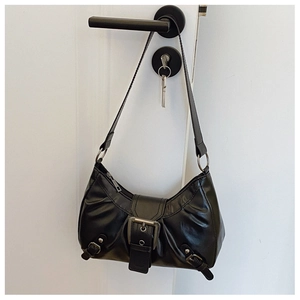 Close-up of black glossy leather shoulder bag with vintage silver metal buckles detail