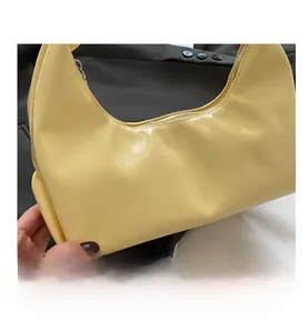 Detailed view of light yellow hobo bag with glossy wrinkled texture and metal zipper