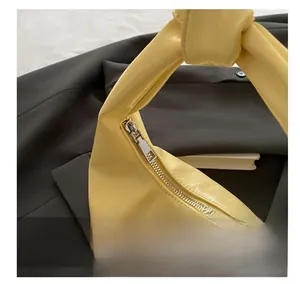 Close-up of smooth silver zipper and glossy oil-wax texture on a yellow handbag