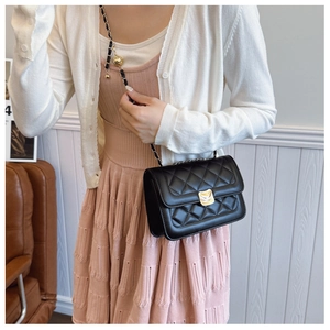 Detail of quilted black shoulder bag with golden ball adjustable chain and metal lock