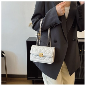 Close-up of white quilted chain shoulder bag with elegant gold curved buckle closure
